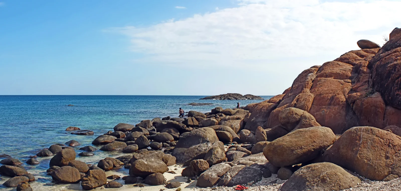The shallow reef and rocky shore of Pigeon Island in clear water.