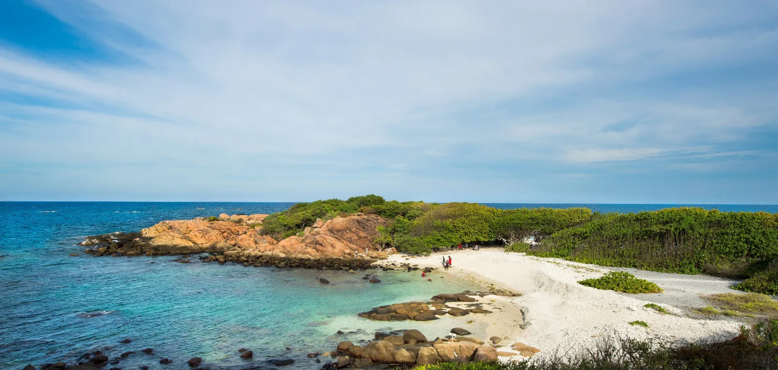 A turquoise cove with a rocky headland and pale sand on the east coast.